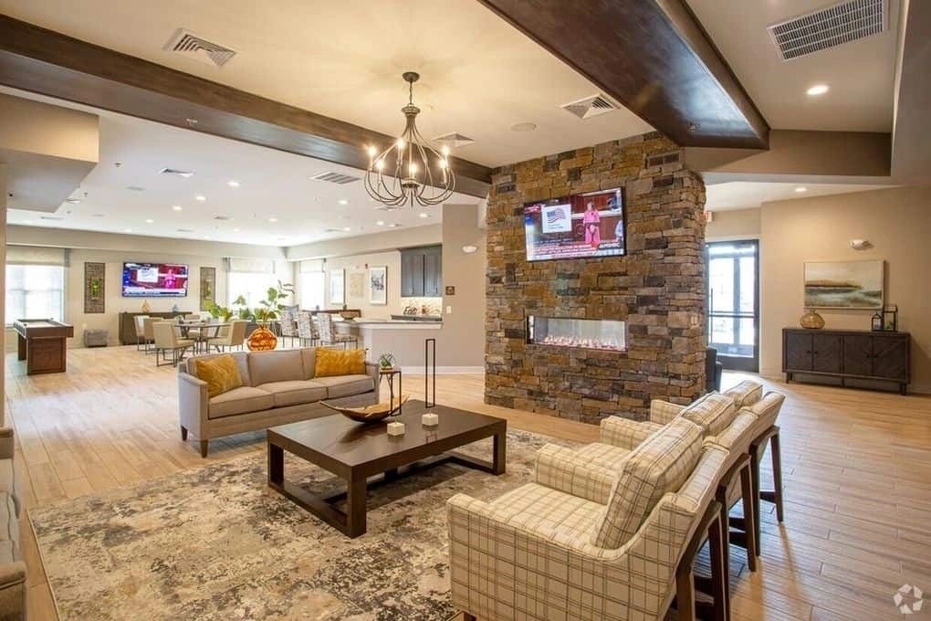 A warm community clubhouse great room with a stacked-stone fireplace and lounge seating